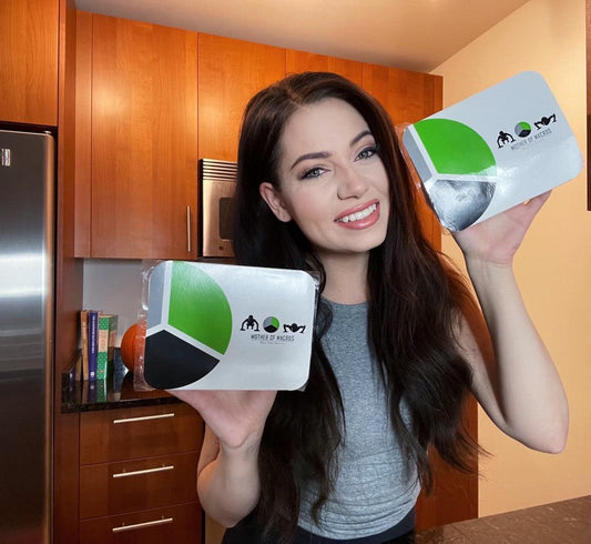 Smiling woman holding meal prep containers in a modern kitchen, promoting healthy meal prep services.